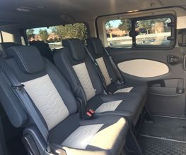 Asientos traseros de una camioneta con tres plazas y ventanas a los lados.