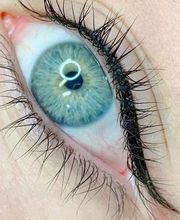 Close-up van een blauw oog met lange wimpers en donkere eyeliner.