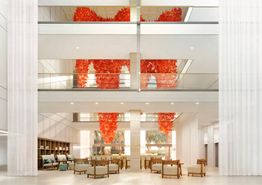 Lobby moderno con sillas y decoración colgante roja en varias plantas.