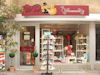 Kleiner Laden mit roten Vordach, Schaufenster voller Spielzeug und Regal mit Grußkarten außen.