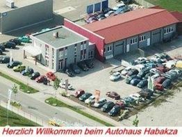 Luftaufnahme eines Autohauses mit vielen geparkten Autos. Text: "Willkommen beim Autohaus Habakza".