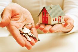 Manos sosteniendo llaves y una miniatura de casa.