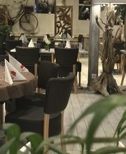 Gemütliches Restaurant mit Holzdekor, gedeckten Tischen und grüner Pflanze im Vordergrund.