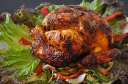 Pollo asado sobre hojas de lechuga y verduras, listo para servir.