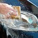 Hand washing a car's headlight with a sponge and suds.