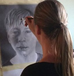 Frau malt ein Porträt eines weinenden Jungen mit Bleistift und Pinsel.