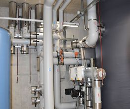 Industrieanlage mit Rohren und Ventilen in einem technischen Raum.