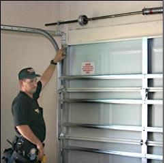 Person inspecting a metal garage door with tools attached to their belt.
