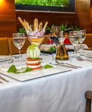 Mesa elegante con platos gourmet, copas de vino, decoración y luz tenue en restaurante acogedor.