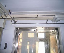 Industriell gestalteter Raum mit Rohren an der Decke und einer verschlossenen Metalltür.