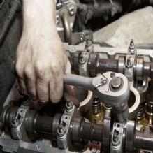 Hand using a wrench to adjust engine components.
