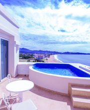 Terraza con piscina pequeña, mesa y sillas, vista al mar y cielo azul.