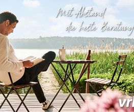 Ein Mann liest am See auf einer Terrasse. Im Hintergrund Text: "Mit Abstand die beste Beratung".