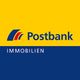 Postbank Immobilien Logo mit gelbem Hintergrund und blauem Bereich unten.
