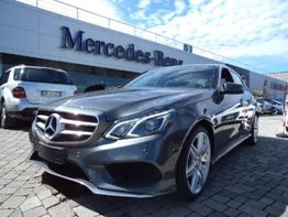Auto Mercedes-Benz grigia parcheggiata davanti a concessionaria, cielo sereno sopra.