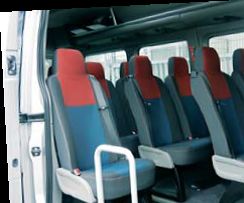 Innenraum eines Kleinbusses mit roten und grauen Sitzen, zwei Sitzreihen sichtbar.