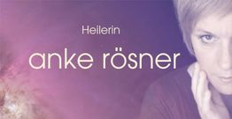 Heilerin Anke Rösner vor lila Hintergrund, Porträtfoto mit verträumtem Ausdruck.