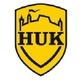 Gelbes Wappen mit schwarzem Schriftzug "HUK" und stilisierter Burg im oberen Bereich.