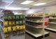 A small grocery store aisle with shelves of snacks and packaged goods.