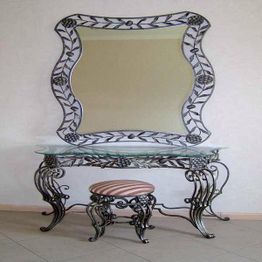 Schminktisch mit geschwungener Verzierung, Glasplatte und Hocker mit gestreifter Polsterung.