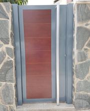 Puerta moderna de madera y metal con marco de piedra gris.