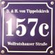 Blaues Metallschild mit weißer Aufschrift: "157c", "D. & H. von Tippelskirch", "Wolfratshauser Straße".