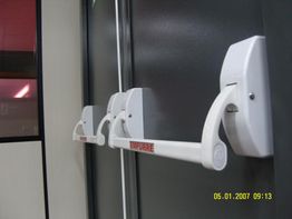 Porta cinza com barra de empurrar branca e etiqueta "EMPURRE". Data na imagem.