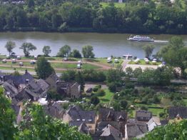 Blick auf ein Dorf am Fluss mit Booten, Bäumen und Häusern am Ufer.