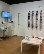 Tienda de gafas con descuento del 50%, paredes blancas y mobiliario moderno.