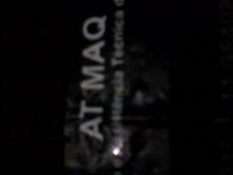 Imagem escura de texto parcialmente legível, com as letras "AT MAQ" em destaque.