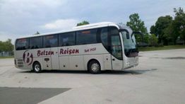 Ein Reisebus von "Betzen-Reisen" auf einem Parkplatz, umgeben von Bäumen und Himmel.