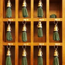 Wooden cubbyholes with green key tassels hanging in a grid arrangement.