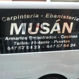 Texto en vehículo de carpintería Musán con servicios y números de contacto.