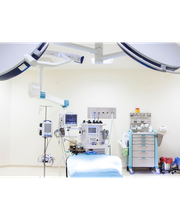 Sala operatoria vuota con macchinari medici e luci chirurgiche.