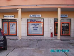 Facciata di un negozio di elettronica con insegne "Riparazioni", "Elettroniche" e "Accettazione".