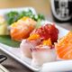 Vassoio di sushi colorato con pesce crudo e uova di pesce, accompagnato da bacchette giapponesi.