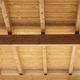 Vista di un soffitto in legno con travi esposte, inquadrato dal basso.
