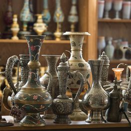 Ornate and colorful vases and pitchers on display in a shop.
