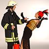 Ein Feuerwehrmann und eine Frau im Kostüm posieren zusammen auf einer Bühne.