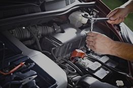 Hands using a wrench to repair a car engine.