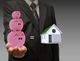 Man holding pink piggy banks equaling a house, symbolizing savings for home buying.