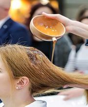 Donna riceve trattamento per capelli con liquido versato da una ciotola.