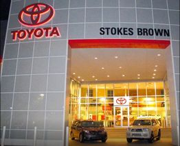 Toyota dealership entrance lit up at night with two cars displayed outside.