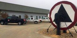 Trucks parked outside a building with a large, circular, triangular sign in the foreground.
