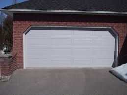 White garage door on a brick house with a snowy driveway.
