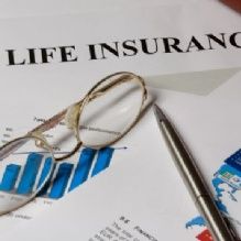 Glasses and pen on a life insurance document with charts and graphs.