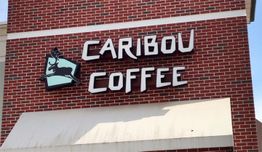 Caribou Coffee sign on a brick wall with a canopy below.