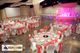 Elegant event hall with round tables, pink decor, and white chairs ready for a reception.