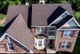 Aerial view of a two-story brick house with a dark roof and surrounding greenery.