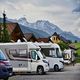 RVs parked near cabins with mountains in the background.